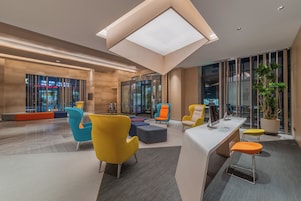 En moderne lobby med et centralt siddeområde, en receptionsdisk og en glas elevator.