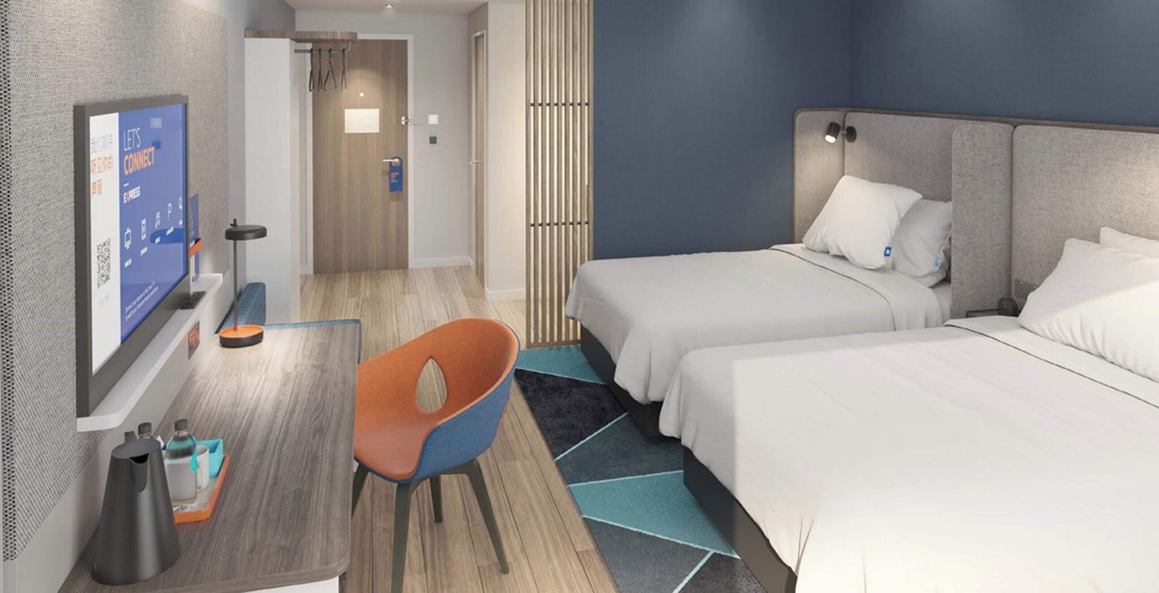 Une chambre d’hôtel avec deux lits, un bureau, une chaise et un téléviseur.