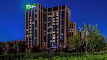 A multi-story hotel with a prominent Holiday Inn Express sign, surrounded by greenery.