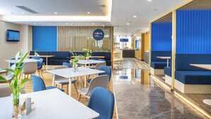 Un moderno vestíbulo de hotel con áreas de descanso, una recepción y una pantalla digital.
