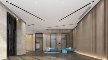 A modern lobby with a high ceiling, recessed lighting, and a seating area with sofas and chairs.