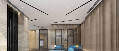A modern lobby with a high ceiling, recessed lighting, and a seating area with sofas and chairs.
