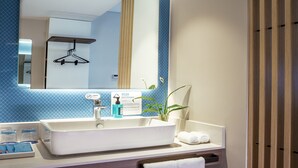 Un baño moderno con un espejo grande, un lavamanos blanco y un perchero para toallas.