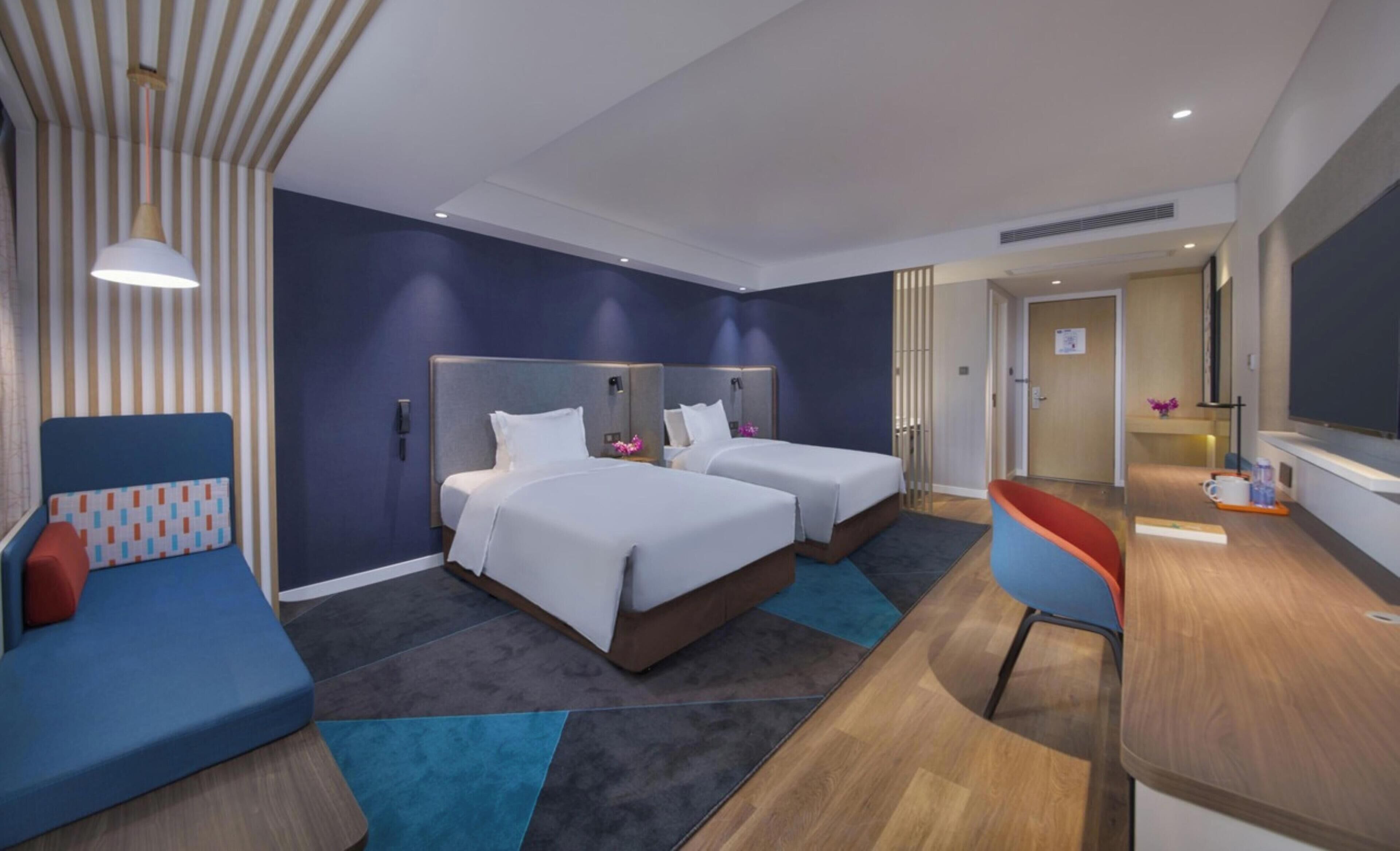 Une chambre d’hôtel avec deux lits, un canapé, un bureau et une télévision.