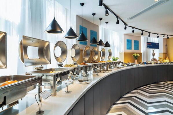 A buffet area with multiple food stations, overhead lighting, and a modern interior design.