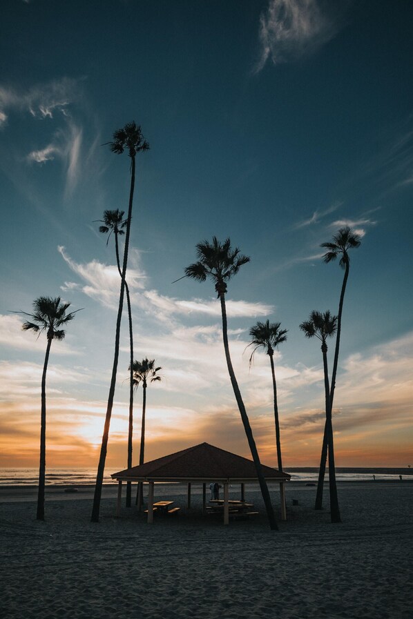 A beach scene with a pavilion and palm trees.