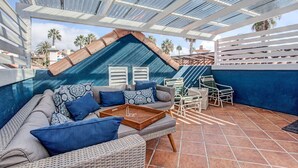 A covered outdoor seating area with a sofa, chairs, and a tray table. - Located in downtown O'side - Blue Jay by the Pier (Oceanside)