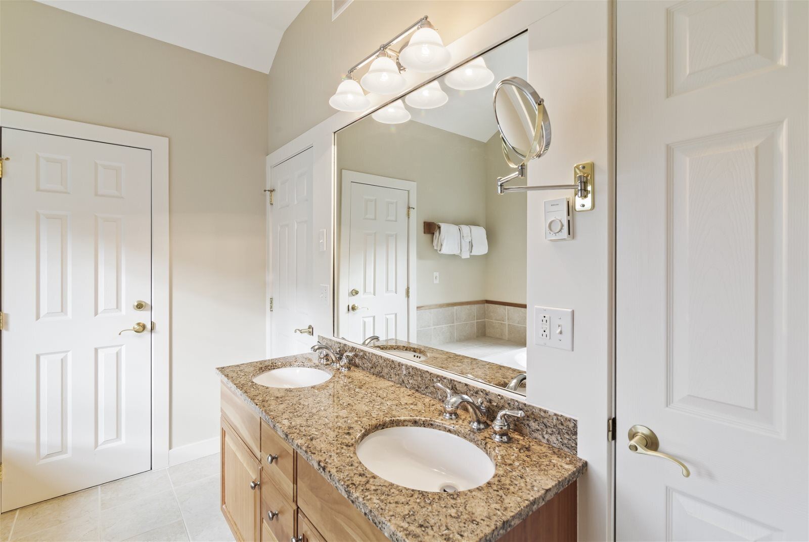 A bathroom with two sinks, a large mirror, and a vanity with drawers.