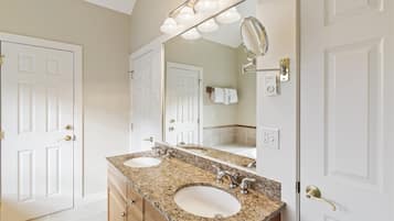 A bathroom with two sinks, a large mirror, and a vanity with drawers.