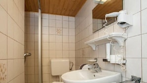 Un baño con ducha, inodoro, lavamanos y un perchero para toallas.