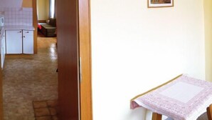 Una habitación de hotel con una cama, una mesita con mantel, una mesita de noche y un cuadro en la pared.