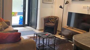 A modern living room with a sofa, a coffee table, a television, and a door leading outside. - Montmartre Moulin rouge Batignolles (Paris)