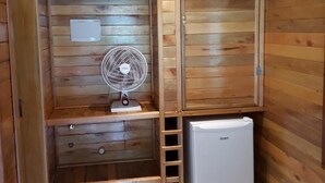 Una habitación pequeña con paredes de madera y ventilador integrado.