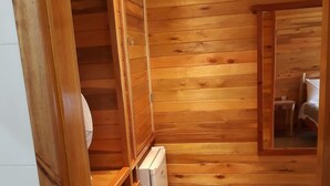 Una habitación pequeña de madera con un banco empotrado, un refrigerador blanco compacto y un cesto de basura.