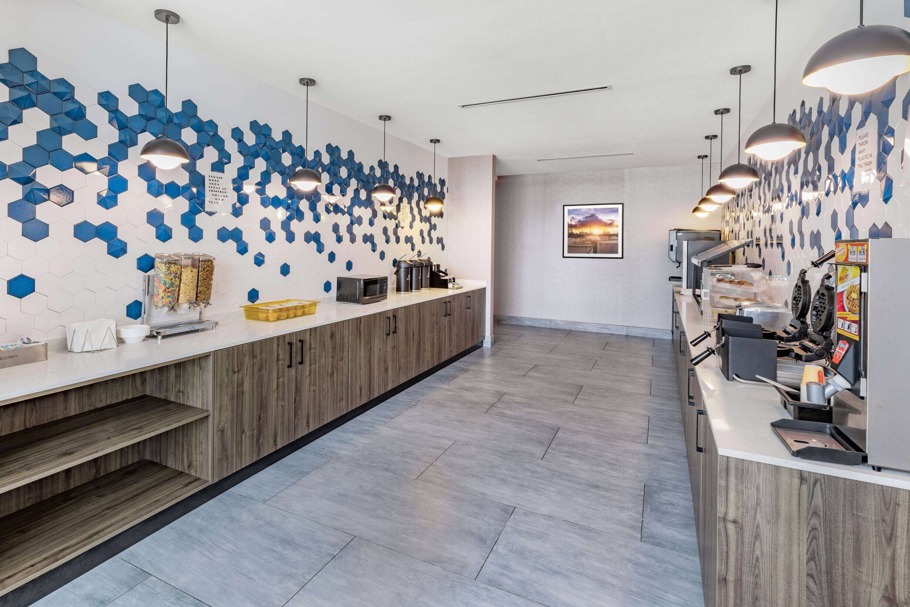 Una cocina moderna con una encimera larga, armarios de madera y una pared decorativa de hexágonos azules.
