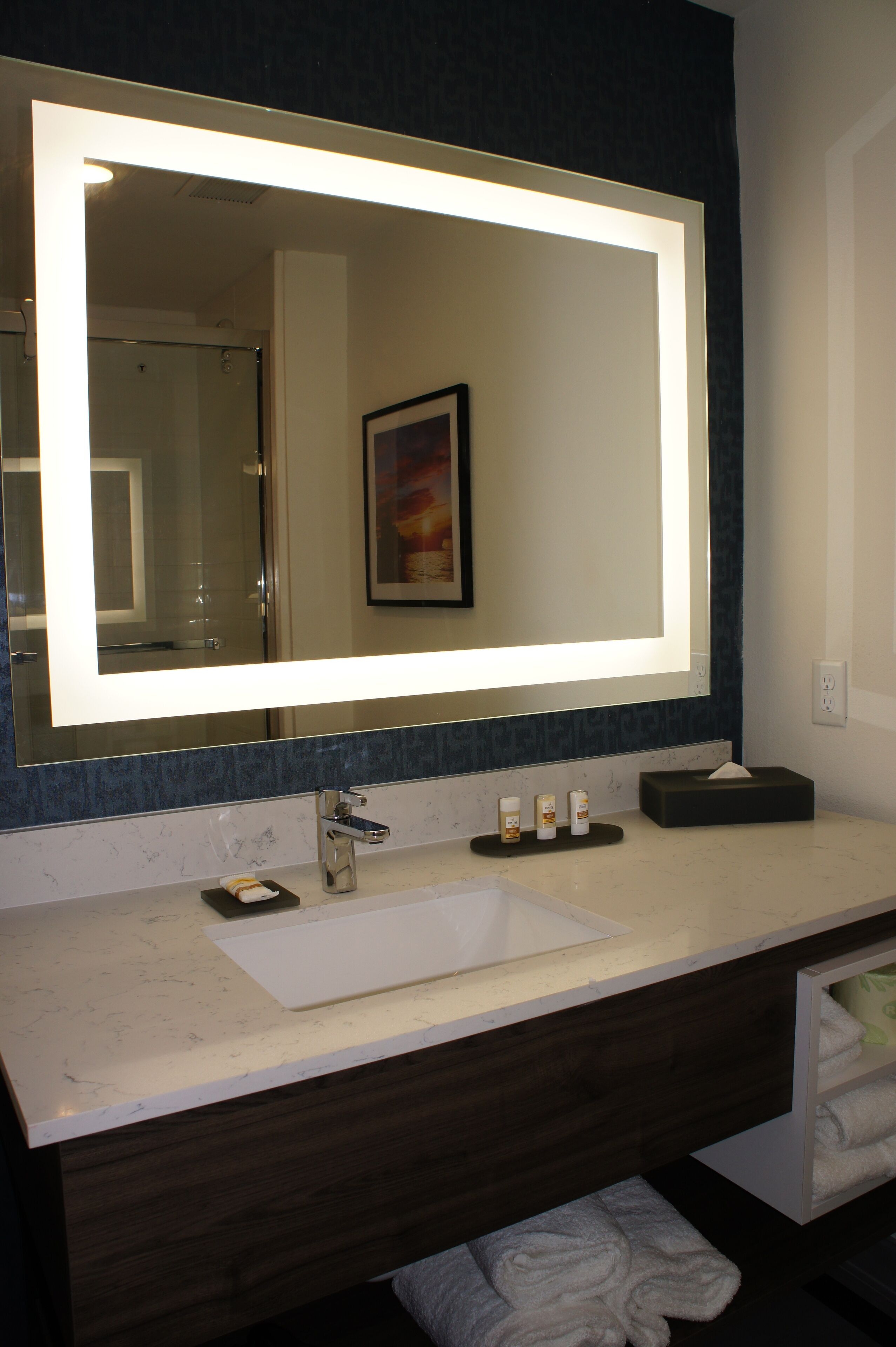 Un baño con un espejo grande, un lavabo y un perchero para toallas.