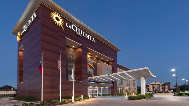 Hotel com design moderno, exibindo uma placa de destaque 'La Quinta' e uma entrada coberta.