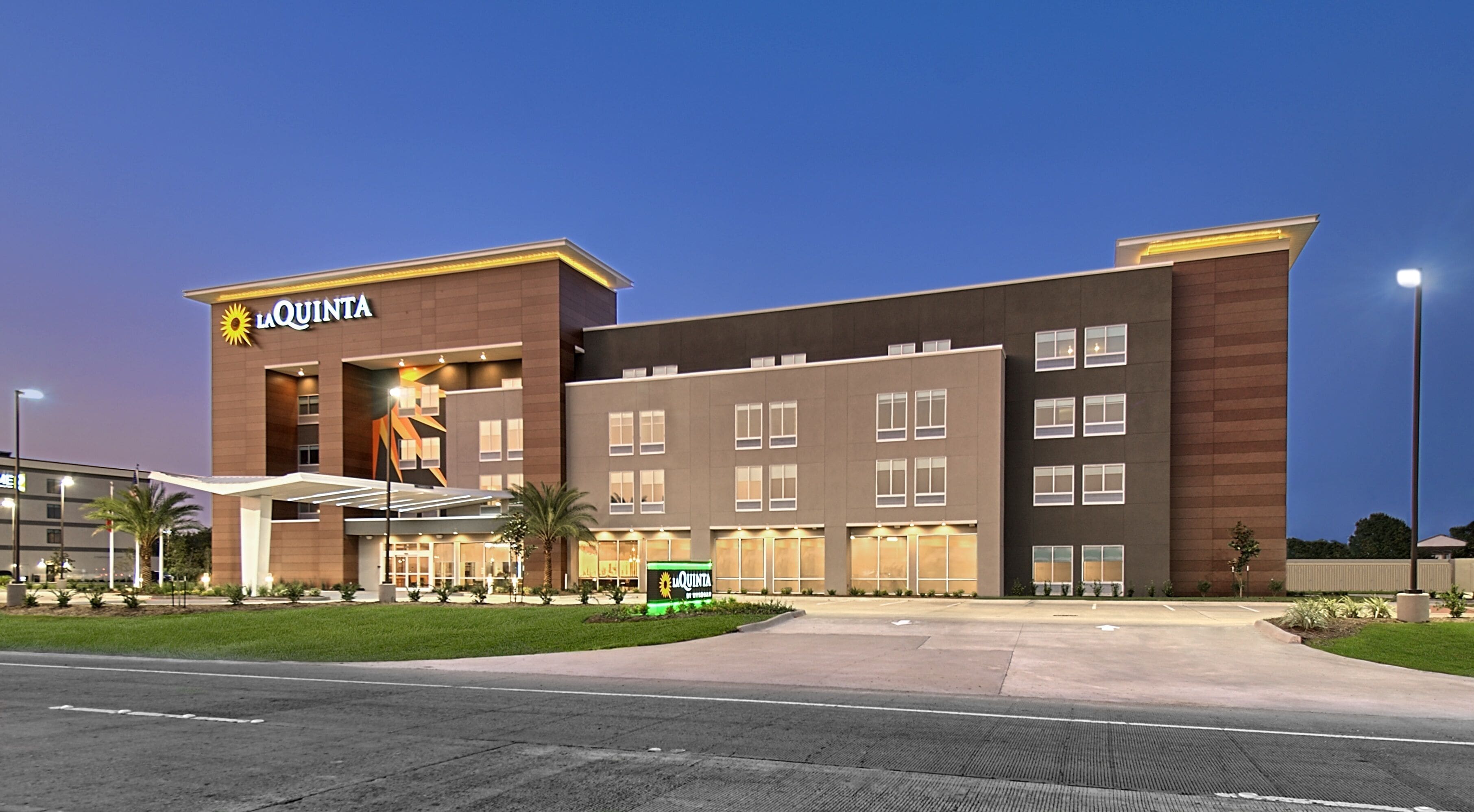 Et La Quinta hotel med moderne design, der har en stor indgang og mange vinduer.