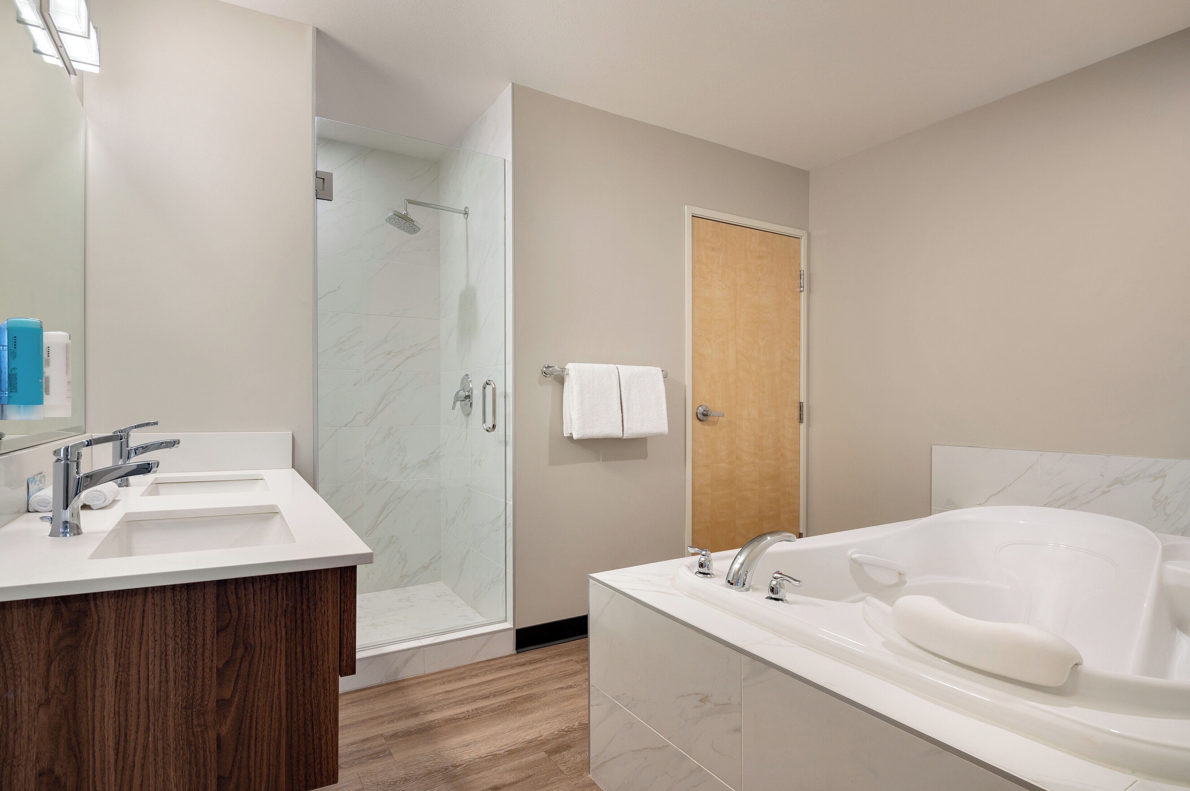 A modern bathroom with a shower, two sinks, and a large bathtub.