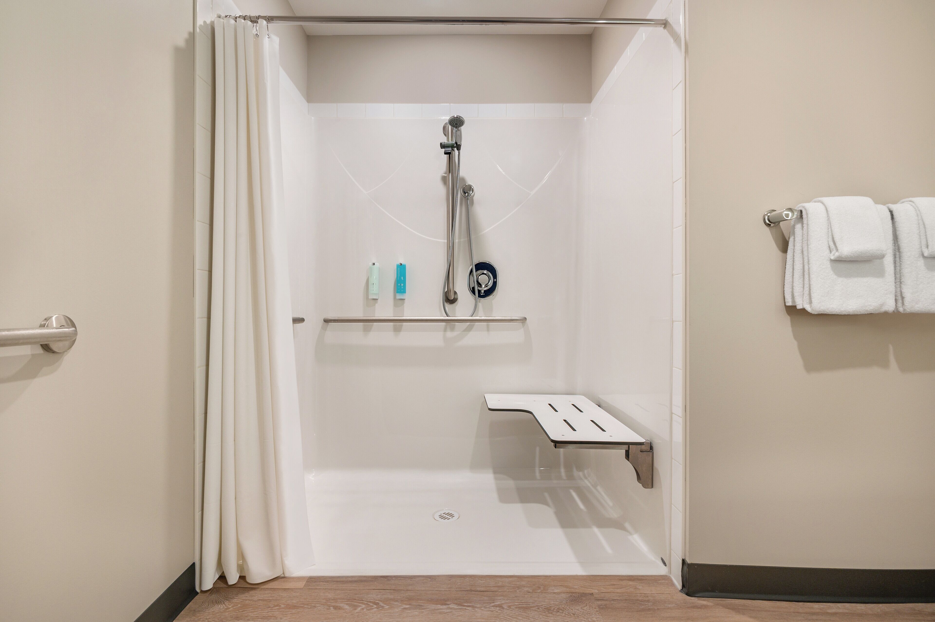 A shower area with a showerhead, a shelf with toiletries, and a towel rack.