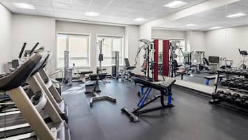 Een fitnessruimte met loopbanden, krachtapparaten en losse gewichten.