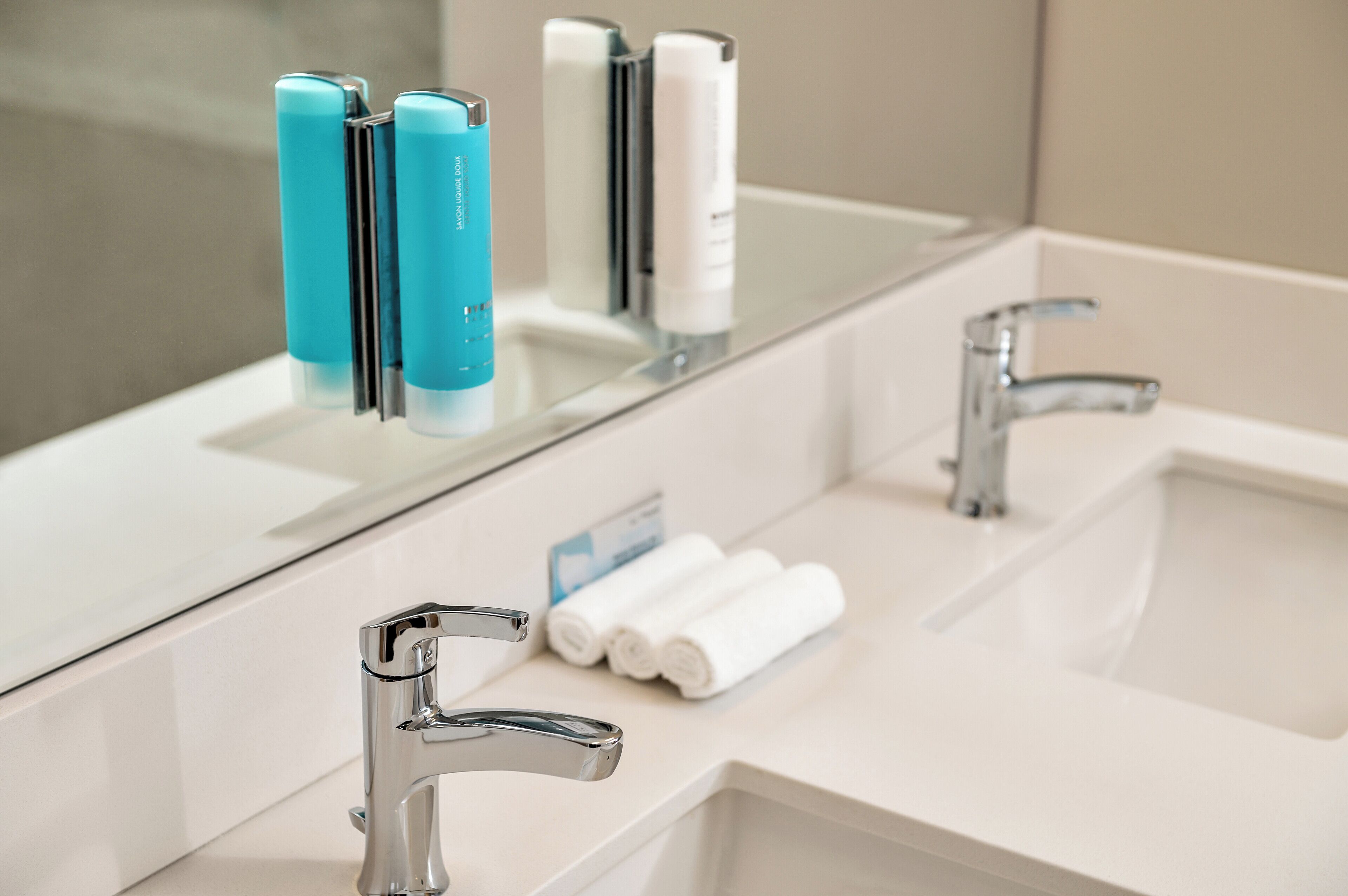 A modern bathroom with two sinks, chrome faucets, and a mirror.