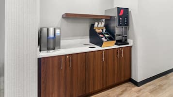 Uma cozinha compacta com cafeteira, geladeira e armário de madeira.