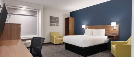 A hotel room with a bed, a desk, a chair, a television, and a wardrobe.