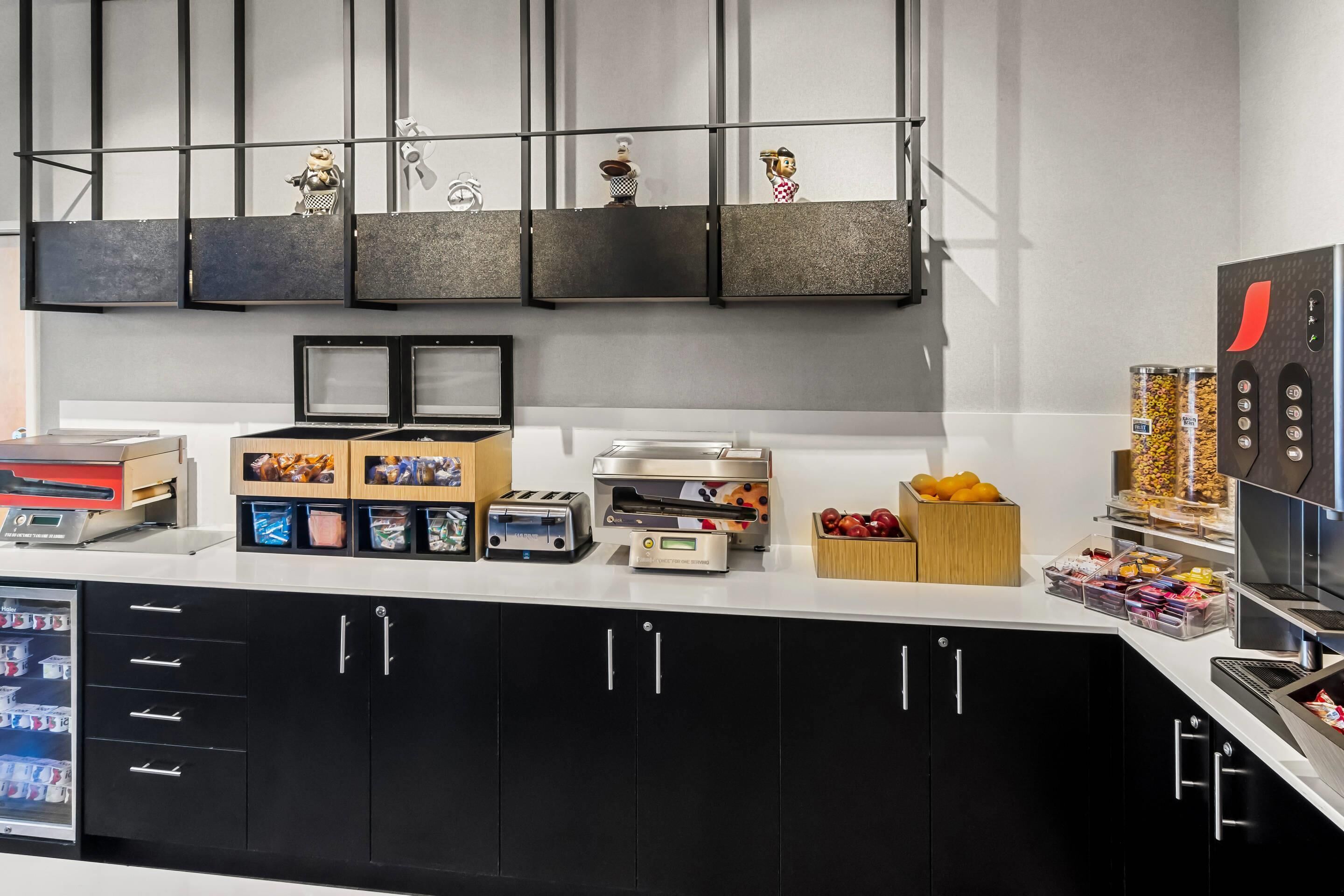 A modern kitchen with black cabinets, a coffee machine, a toaster, and various food containers.