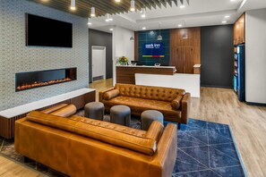Un espace d’accueil moderne avec une cheminée, des canapés en cuir et un comptoir de réception.