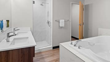 Un bagno moderno con una vasca da bagno spaziosa, due lavabi, una doccia e un mobile bagno in legno.