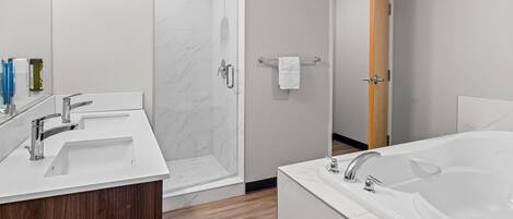 Un baño moderno con una bañera grande, dos lavamanos, ducha y tocador de madera.