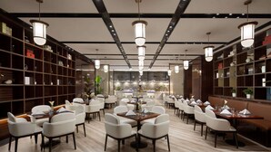 Un comedor amplio con varias mesas y sillas, una barra central y estanterías a lo largo de las paredes.