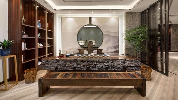 Un interior moderno con un banco de madera, una estantería y una pared decorativa con un espejo circular.