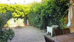 A patio area with a tiled floor, a table with chairs, and a small table with a bench.