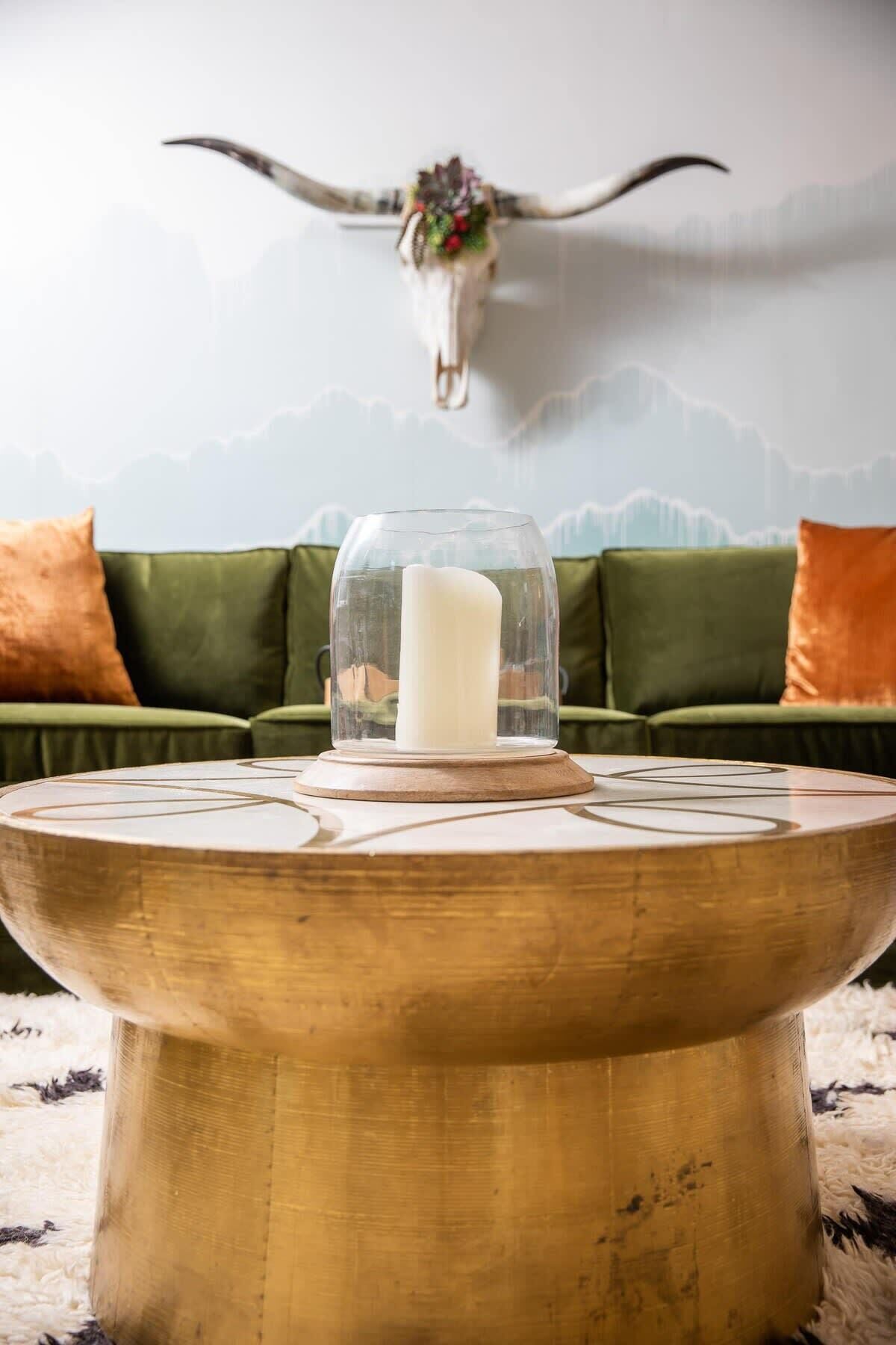 A round wooden table with a glass dome candle holder in the center.