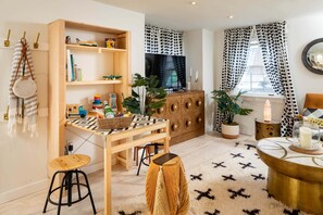 Un salon chaleureux avec une bibliothèque en bois, un téléviseur, une table à manger et un coin salon confortable.