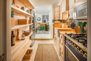 Une cuisine avec des meubles de rangement en bois, une cuisinière et un coin repas comprenant une table et des chaises.