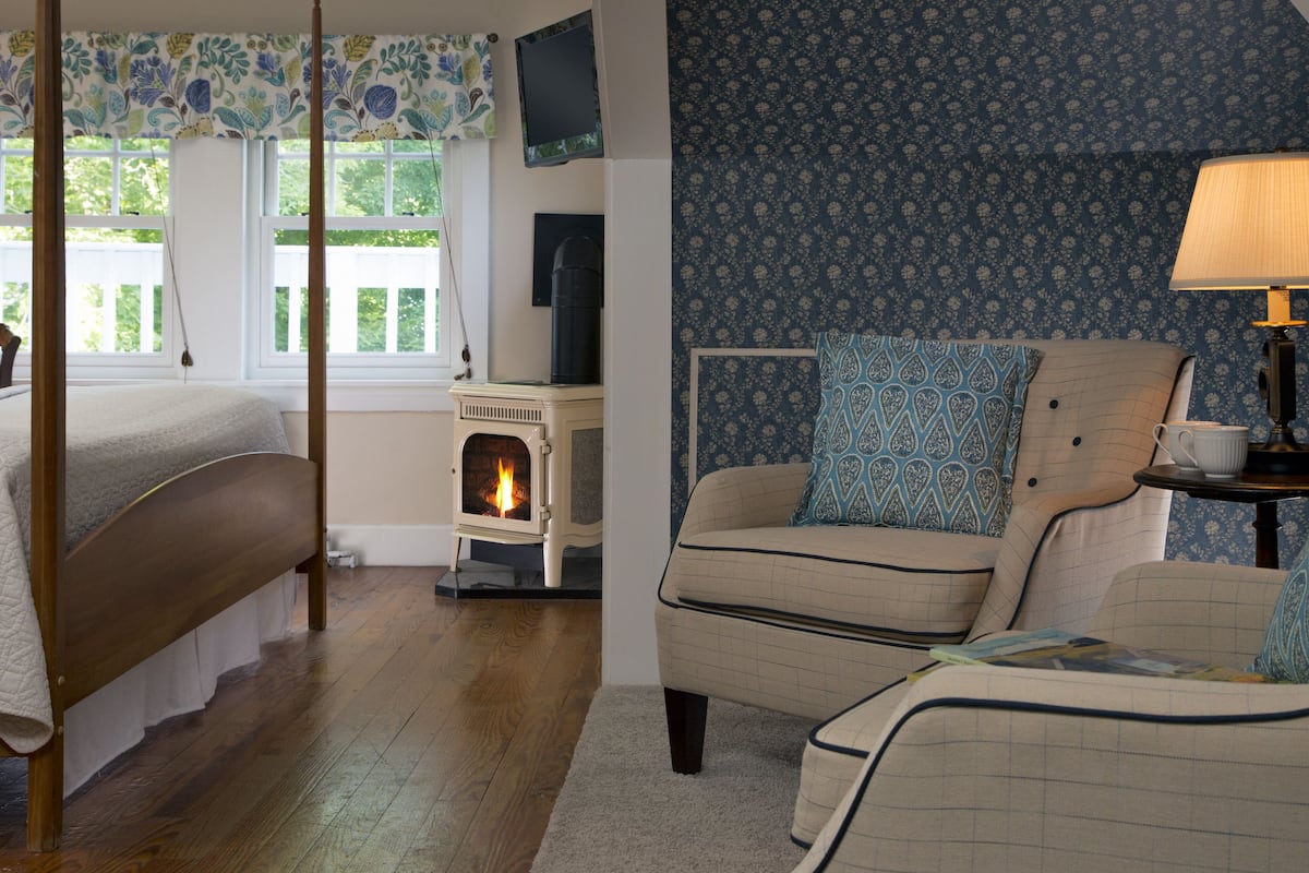 A bedroom with a bed, a fireplace, a sofa, and a television.