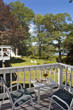 Relax in this serene outdoor seating area with a deck, comfortable chairs, and a charming table setting.
