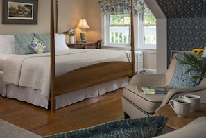 Relax in a spacious room with a four-poster bed, comfortable sofa, and decorative artwork.