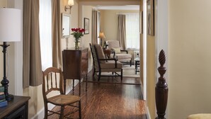 A hallway with wooden flooring, a wooden chair, a table with a lamp, and a vase with flowers. - Newcastle Inn (Newcastle)