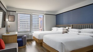 Une chambre d’hôtel avec deux lits, un bureau, une chaise et une grande fenêtre donnant sur la ville.