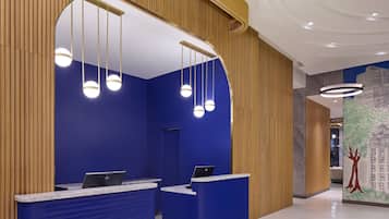A reception area with a blue wall and wooden paneling, featuring a reception desk with a laptop and a large mirror above it.