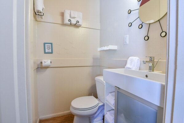 Baño pequeño y limpio con inodoro, lavamanos y perchero para toallas.