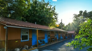 A motel with a row of rooms, each with a door and window, and a covered outdoor seating area with tables and chairs. - Kokopelli Lodge (Moab)