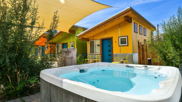 Un jacuzzi dans un jardin, avec une maison en arrière-plan.