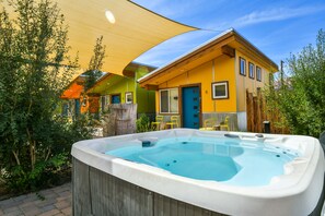 Uma banheira de hidromassagem em um quintal com uma casa ao fundo.
