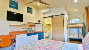 Une chambre d’hôtel compacte comprenant un lit, un bureau, une chaise, une télévision, un four à micro-ondes et un placard à porte coulissante.