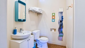 Une petite salle de bain avec un lavabo blanc, un miroir, des toilettes et un porte-serviettes.